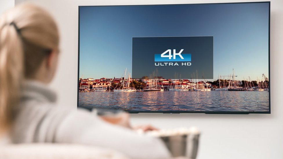 Mujer viendo un televisor en 4K.