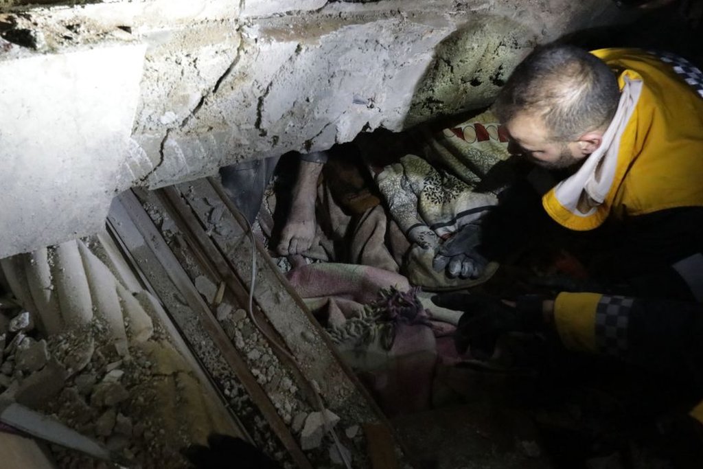 رجال إنقاذ سوريون يحاولون انتشال رجل مصاب من تحت أنقاض مبنى منهار إثر الزلزال في بلدة أعزاز الحدودية شمالي محافظة حلب مطلع 6 شباط 2023