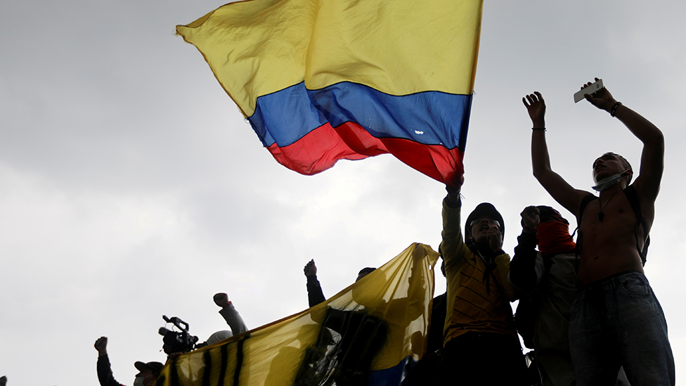 Manifestantes protestan con una bandera de Colombia