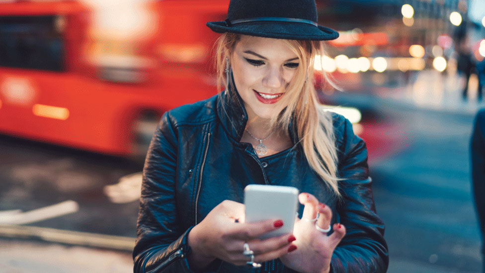 Mujer joven en la calle con su celular