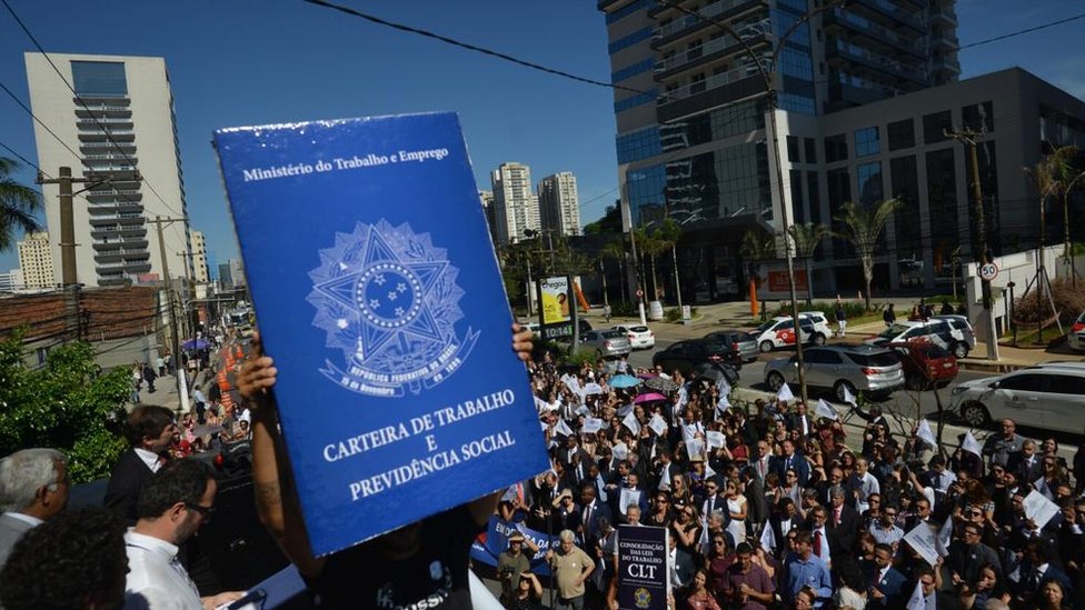 Manifestantes seguram uma carteira de trabalho gigante em protesto contra a possível extinção da Justiça do Trabalho (São Paulo, janeiro de 2019)