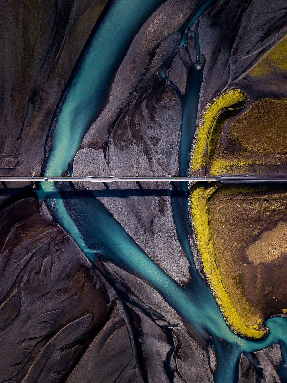 Вид с воздуха на землю, показывающий темный песок с прорезавшей его синей рекой