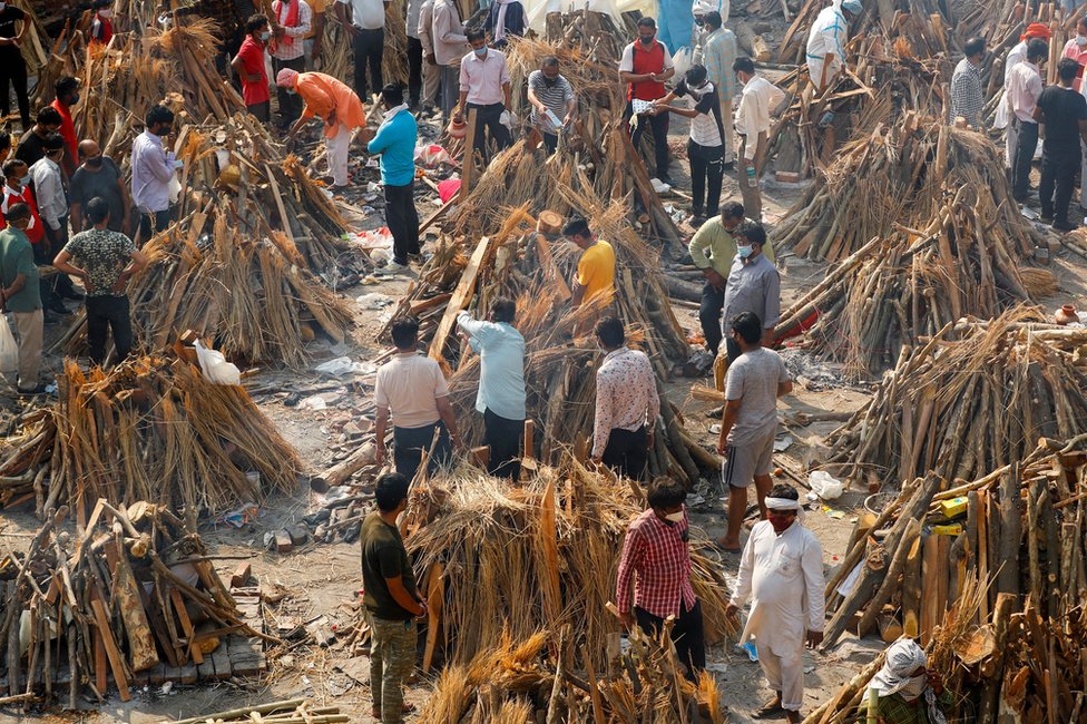 People prepare funeral pyres for a mass cremation in New Delhi, India