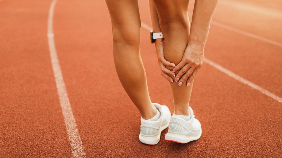 Imagen de las piernas de una corredora en la pista de entrenamiento.