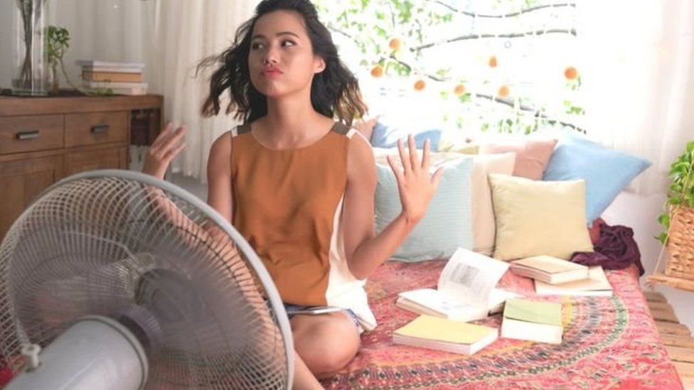 Mujer refrescándose frente a un ventilador