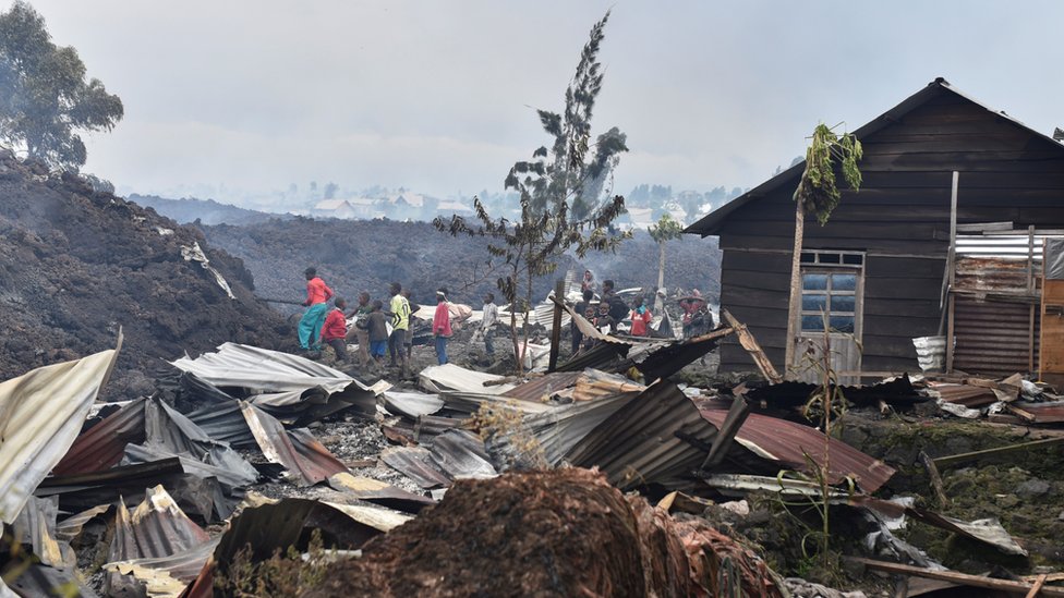 Residents pick up remains of their destroyed homes from the smouldering lava deposited by the eruption of Mount Nyiragongo volcano near Goma