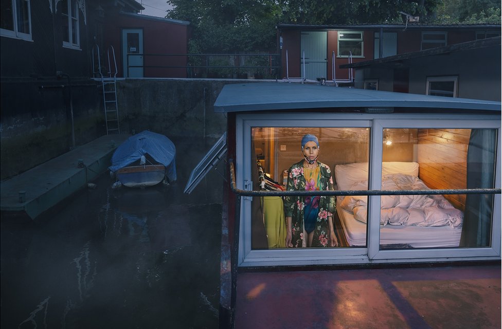 A woman looking out of the window of a house boat