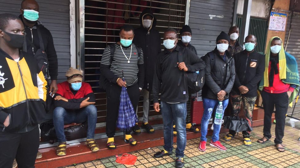 Люди, стоящие у магазина в масках