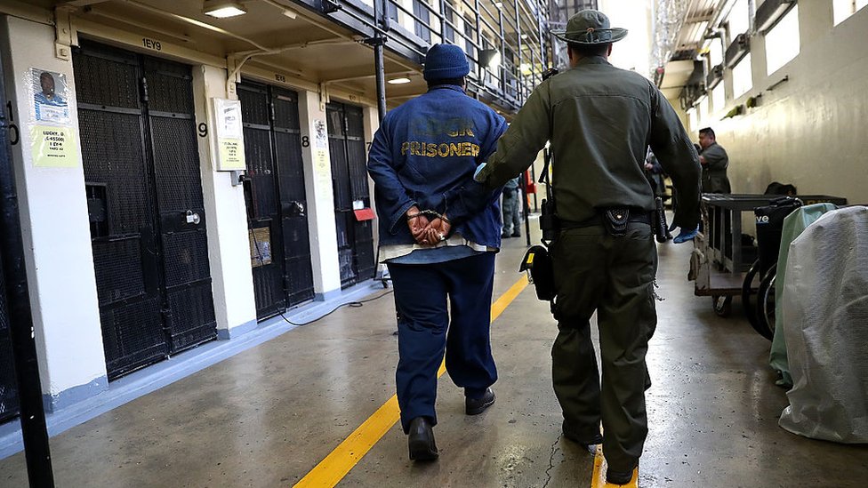 Вооруженный сотрудник Калифорнийского Департамента исправительных учреждений и реабилитации (CDCR) сопровождает осужденного заключенного в камере смертников государственной тюрьмы Сан-Квентин 15 августа 2016 года в Сан-Квентине, Калифорния