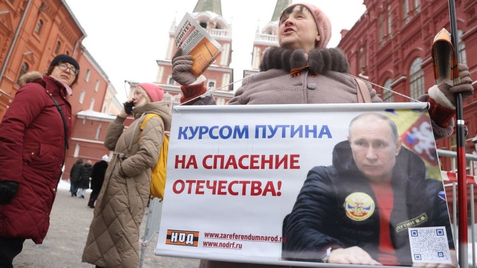 A Putin supporter holds a poster in Red Square ahead of the 2024 election