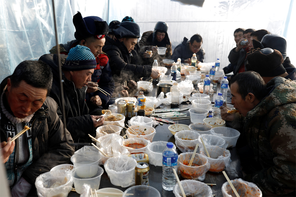 Workers eat lunch inside a makeshift canteen