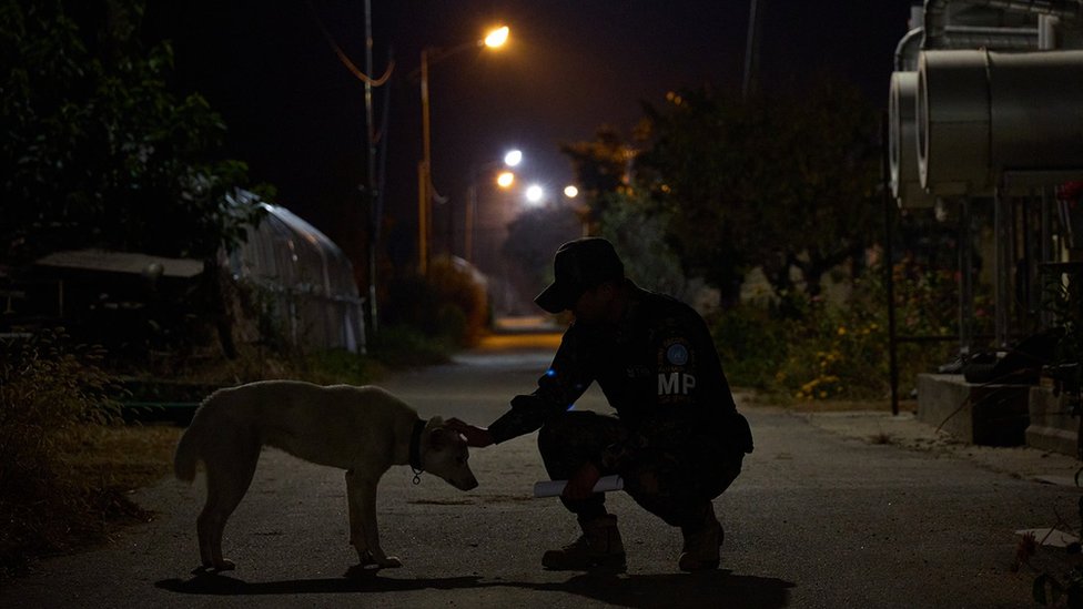 Soldier patrolling the village pets a dog