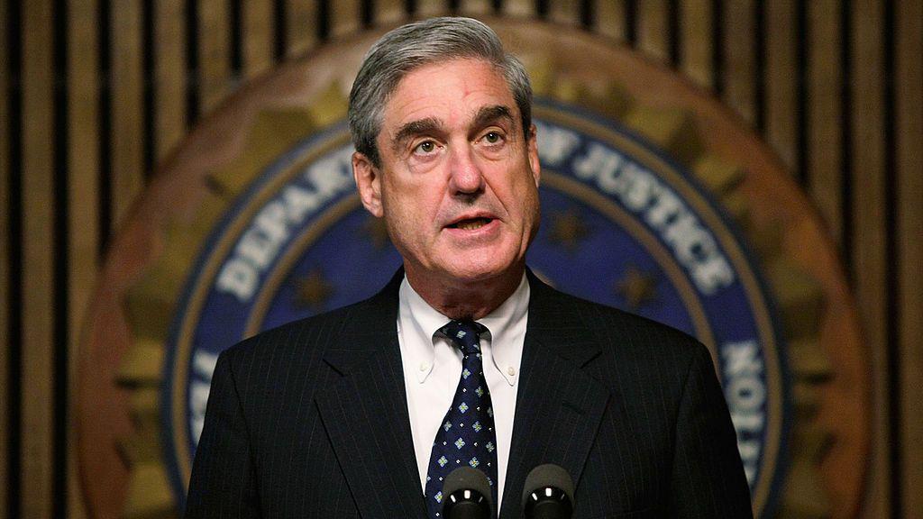 Robert Mueller speaks at a podium while wearing a dark suit.