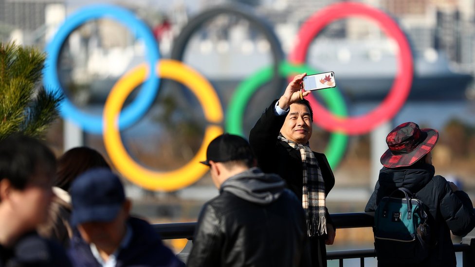 Members of the public get pictures near the Olympic rings on Tokyo