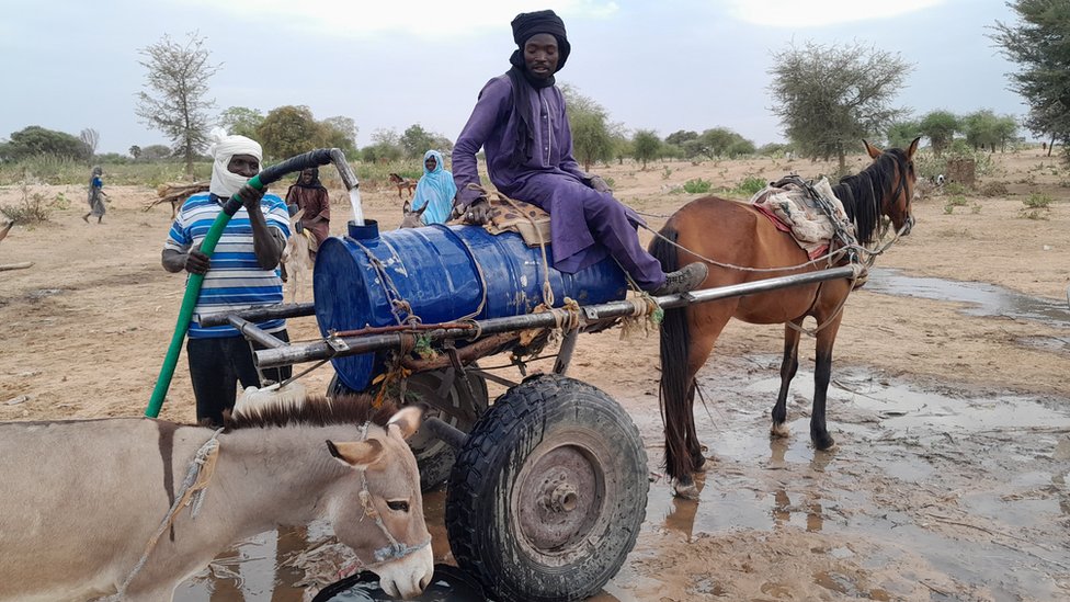 نازح سوداني فر من العنف في بلاده، يملأ برميل مياه ليبيعه لنازحين آخرين بالقرب من الحدود بين السودان وتشاد