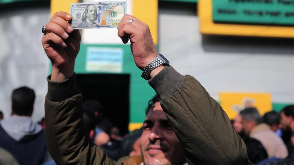 Palestinian man holds up dollar bill