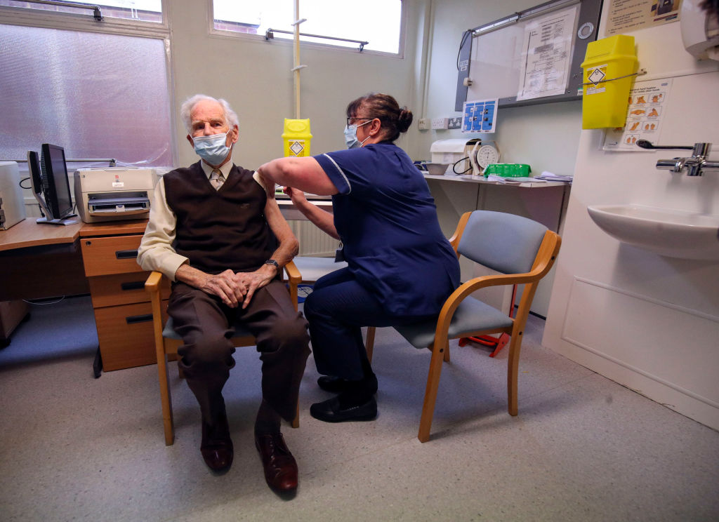 Брайан Хорн получает вакцину от медсестры в приемной терапевта в Чалфонт-Сент-Питер