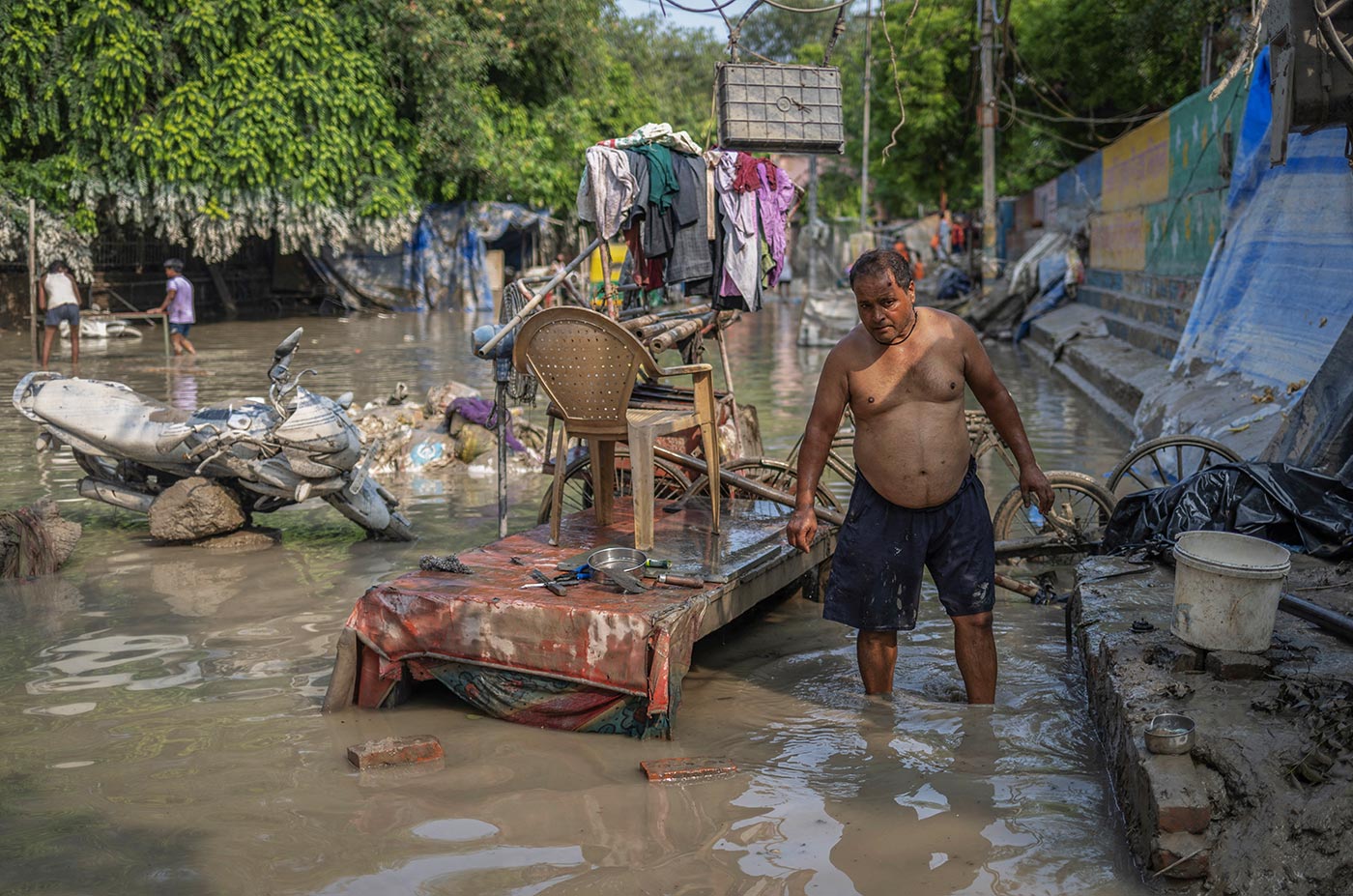 ​​Man cleans his roadside shop after flood waters recede in New Delhi - 17 July 2023