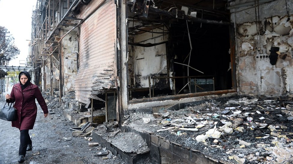 20 November 2019, woman walking by a burned out bank branch