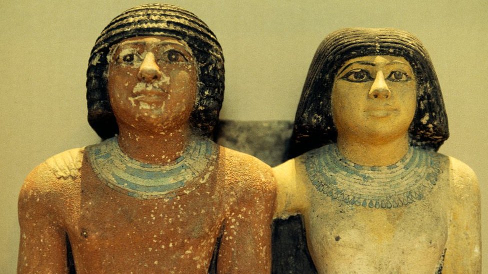 تمثال لشخص من عصر الدولة القديمة وإلى جوراه زوجته وتضع مساحيق التجميل والشعر المستعار