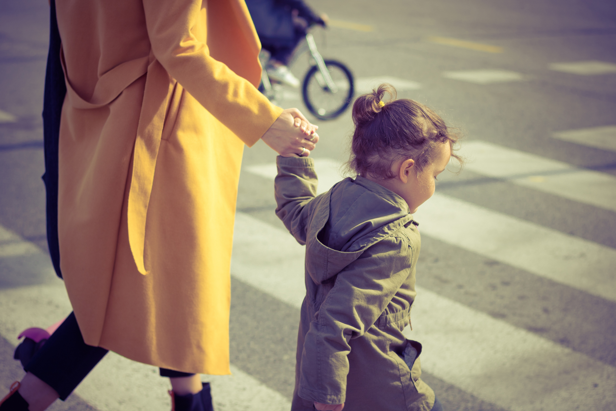 Menina atravessando a rua de mãos dadas com a mãe
