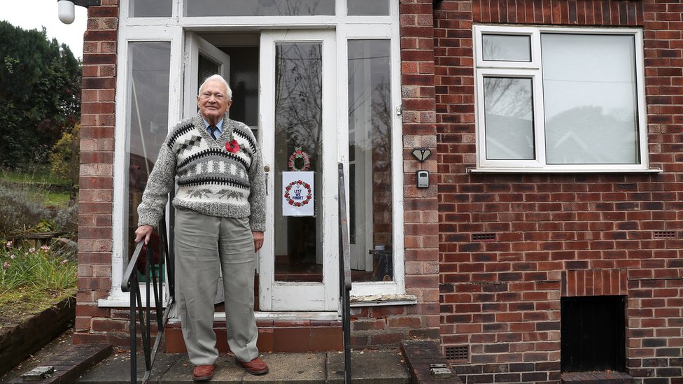 Ветеран Второй мировой войны Джон Маффи 93, стоит на пороге своего дома в Натсфорде, графство Чешир, во время двухминутного молчания