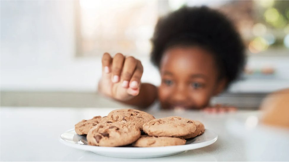 Menina negra pegando biscoito