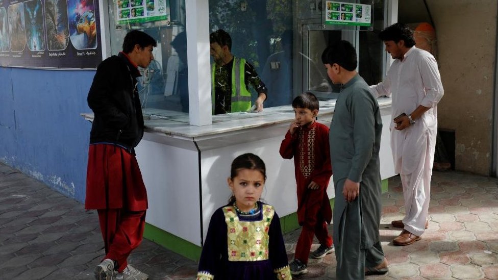 طفلة صغيرة تقف أمام كشك لبيع التذاكر في مدينة ملاهي في كابل