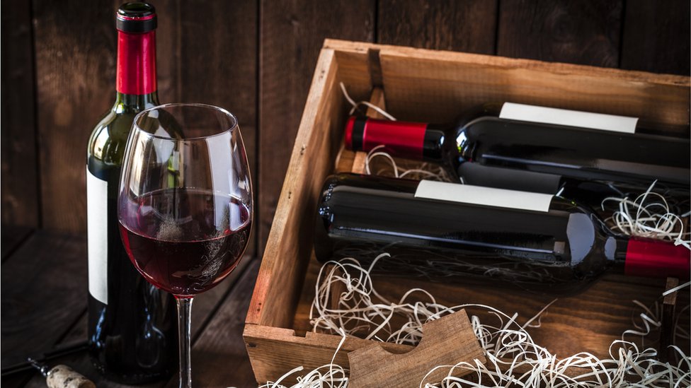 Стакан красного вина и бутылки в деревянном ящике