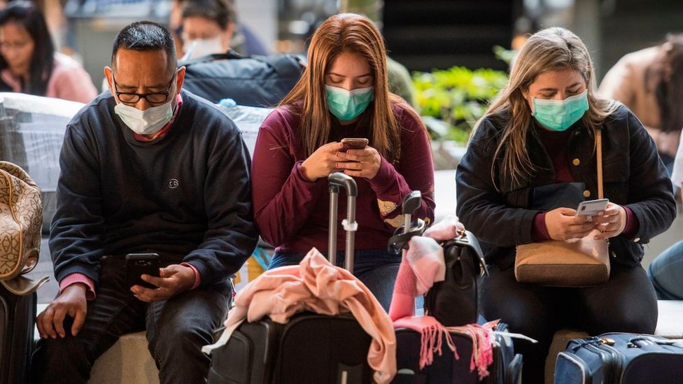Пассажиры носят маски для защиты от распространения коронавируса, когда они прибывают рейсом из Азии в аэропорт Лос-Анджелеса
