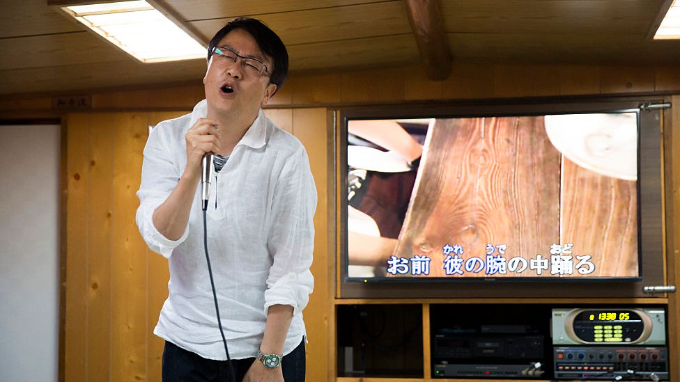 Un japonés canta una canción en un karaoke.