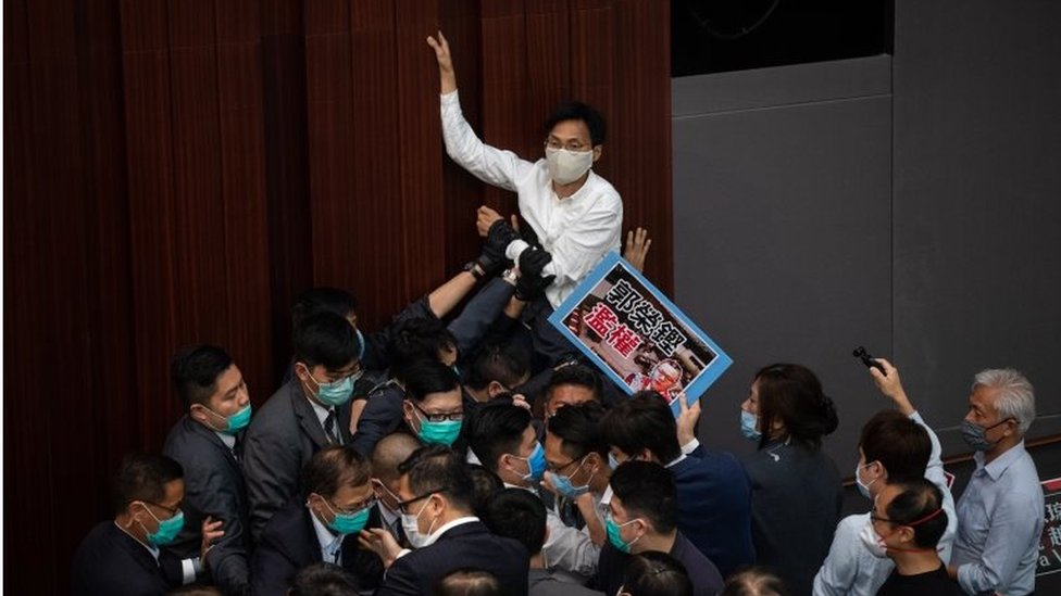 Сторонник демократии Эдди Чу Хой-Дик (в центре) пытается взобраться на стену во время заседания комитета палаты представителей в Законодательном совете Гонконга, Китай, 8 мая 2020 г.
