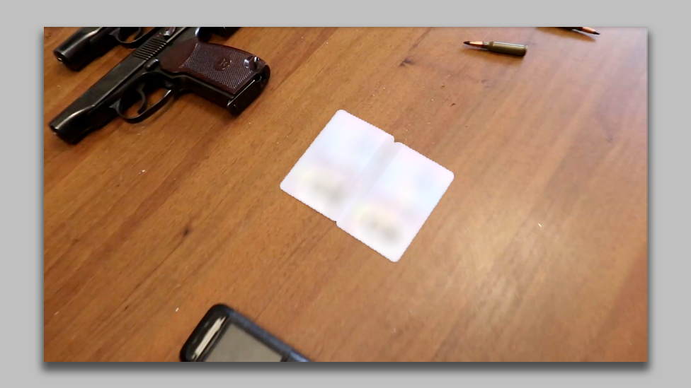 The blurred out ID cards of two Moroccan men on a table next to two handguns and bullets