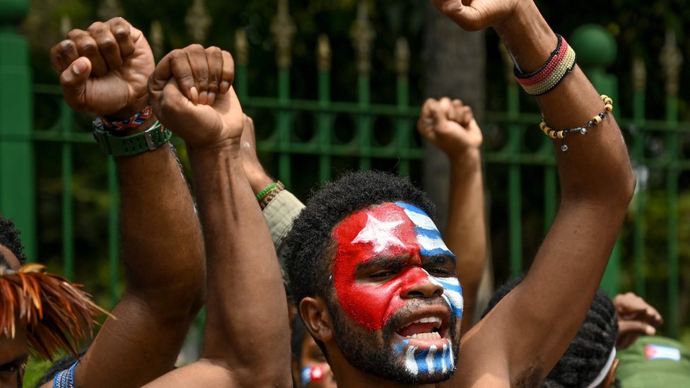 Протестующие поднимают кулаки с нарисованным на лице флагом «Утренняя звезда»