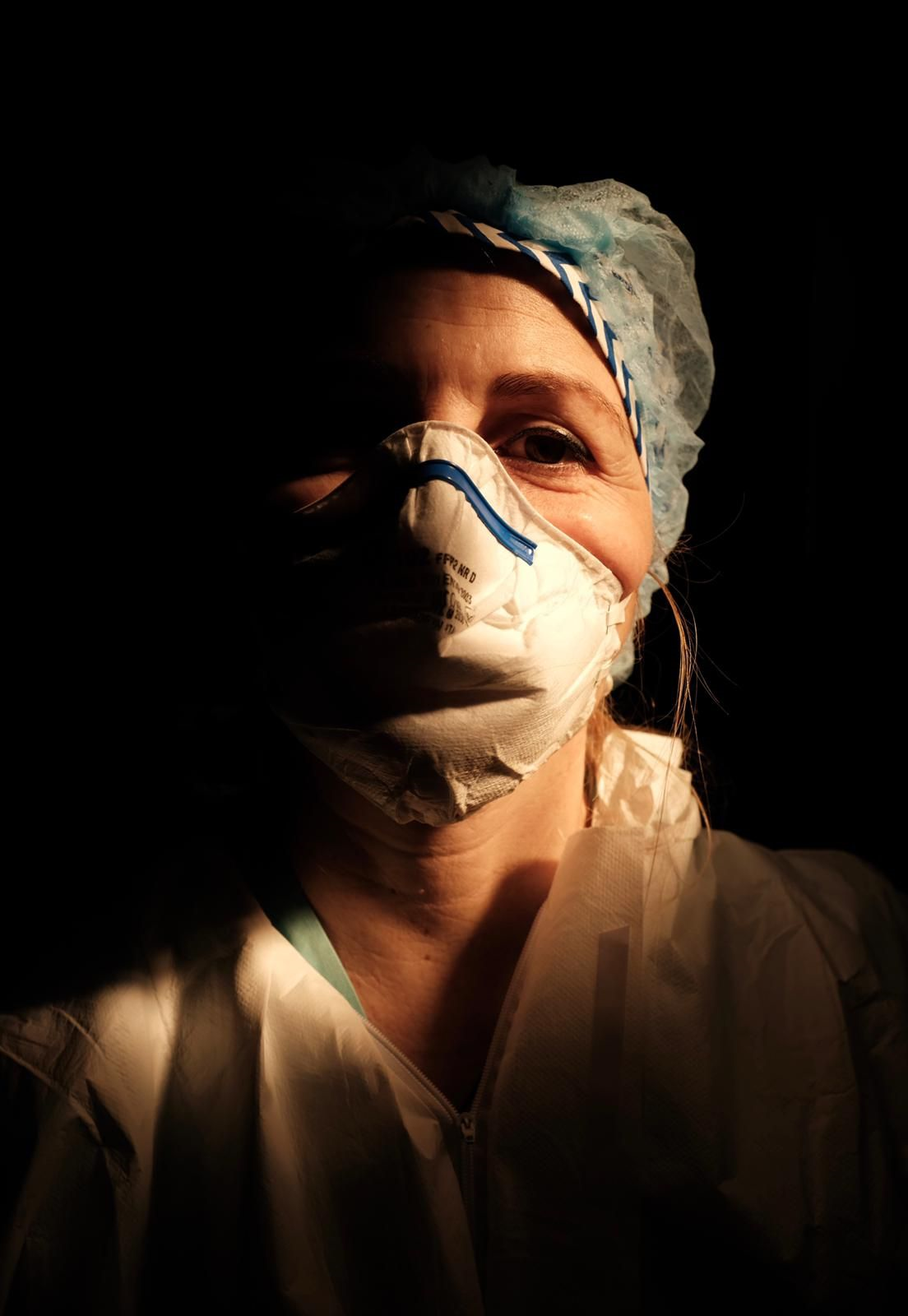 Una enfermera con la cara cubierta con una máscara en un entorno oscuro