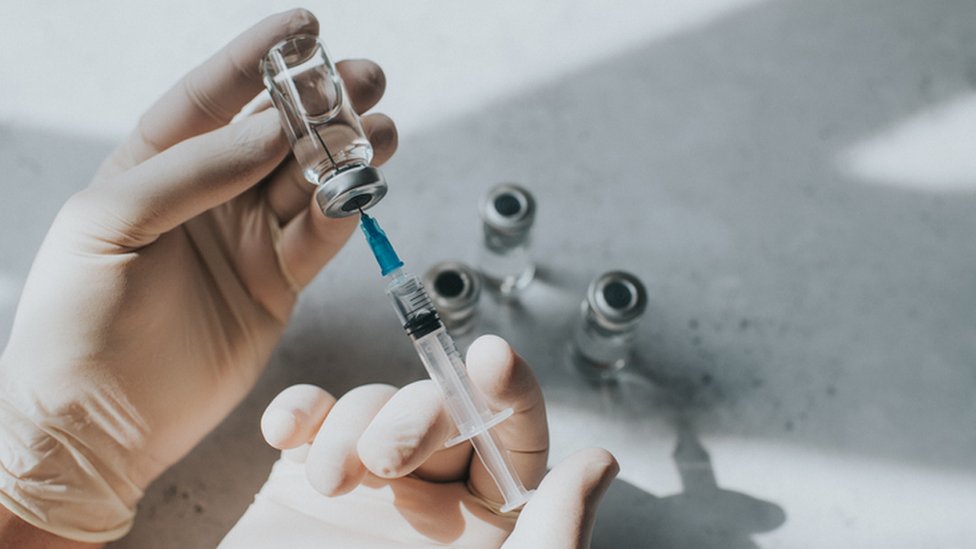 Profissional de saúde tirando vacina de ampola