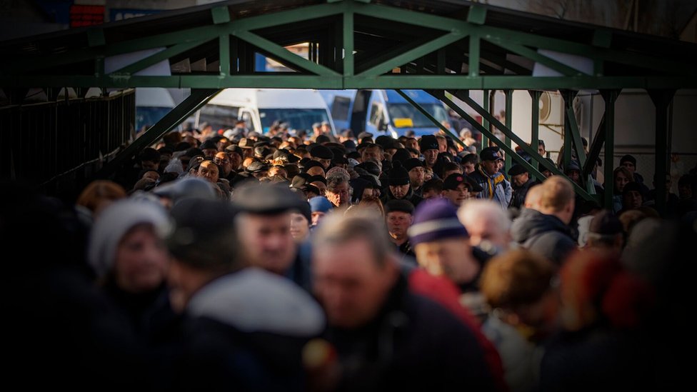 Gente apretujada haciendo cola en la línea del frente entre los territorios controlados por Ucrania y por separatistas prorrusos