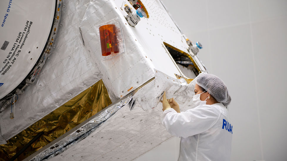 Mujere cosiendo a mano una de las mantas de aislamiento en los satélites