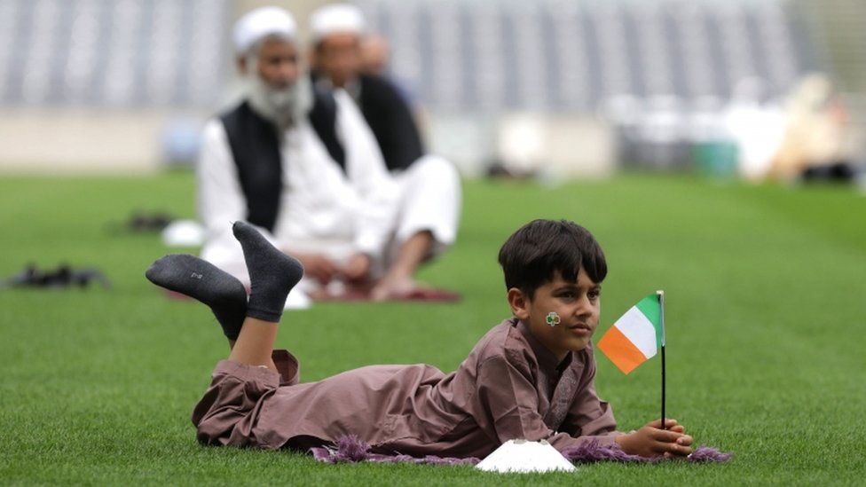 Шестилетний мальчик держит ирландский флаг во время праздника Курбан-байрам в Крок-парке