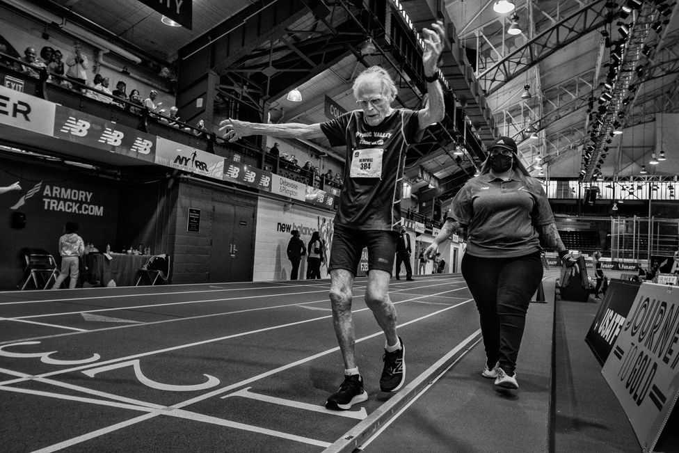 Dikson Hemfil (97) prelazi cilj u trci na 200 metara M95 (muškarci 95-99) u trčanju na 200 metara, u pratnji mlade žene radi bezbednosti.