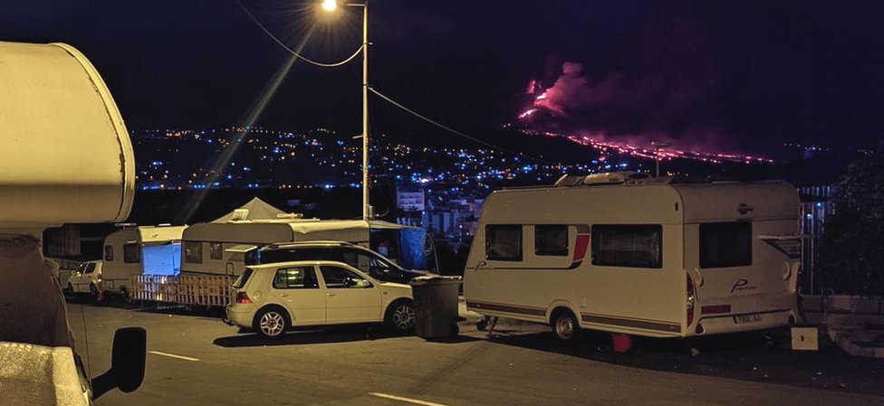 Los que se quedaron sin casa miran la erupción de noche desde sus caravanas.