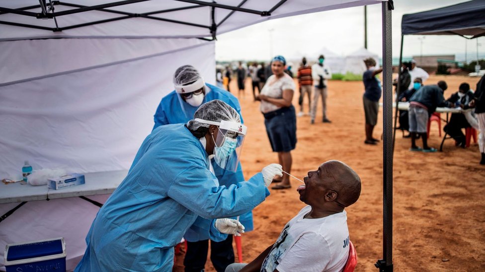 Мужчина, житель обширного городка Александра в Йоханнесбурге, открывает рот, чтобы получить мазок для тестирования на коронавирус COVID-19 на скрининге и тестировании перед хостелом Madala 27 апреля 2020 года.
