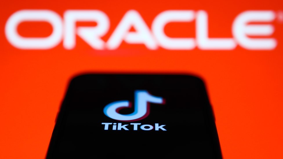 TikTok на экране мобильного телефона перед логотипом Oracle