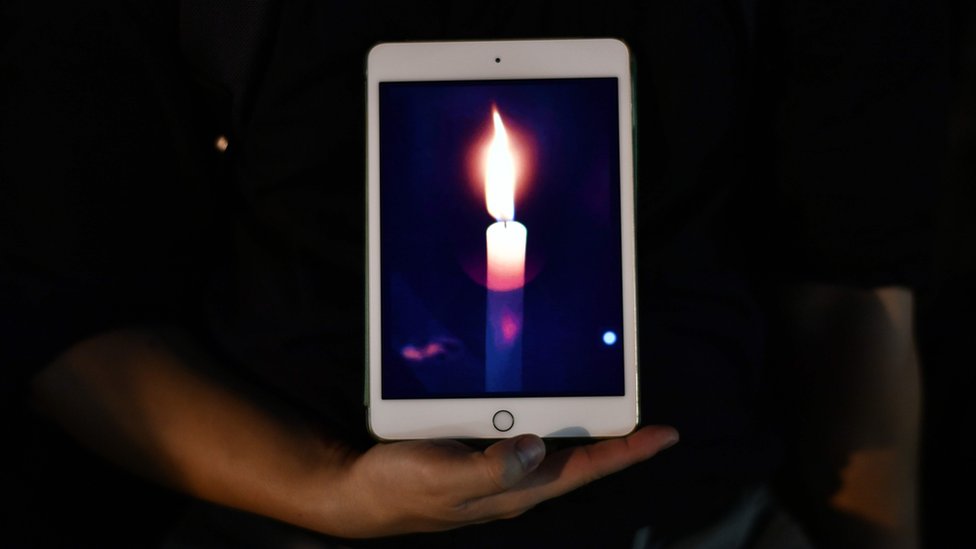 person holds tablet showing candle