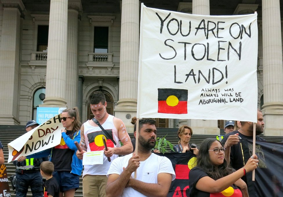 Протестующие из числа аборигенов держат плакаты во время демонстрации перед зданием парламента штата Виктория в День Австралии в Мельбурне, Австралия, 26 января 2017 года.