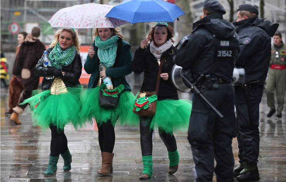 Любители карнавала проходят в Кельне мимо сотрудников немецкой полиции