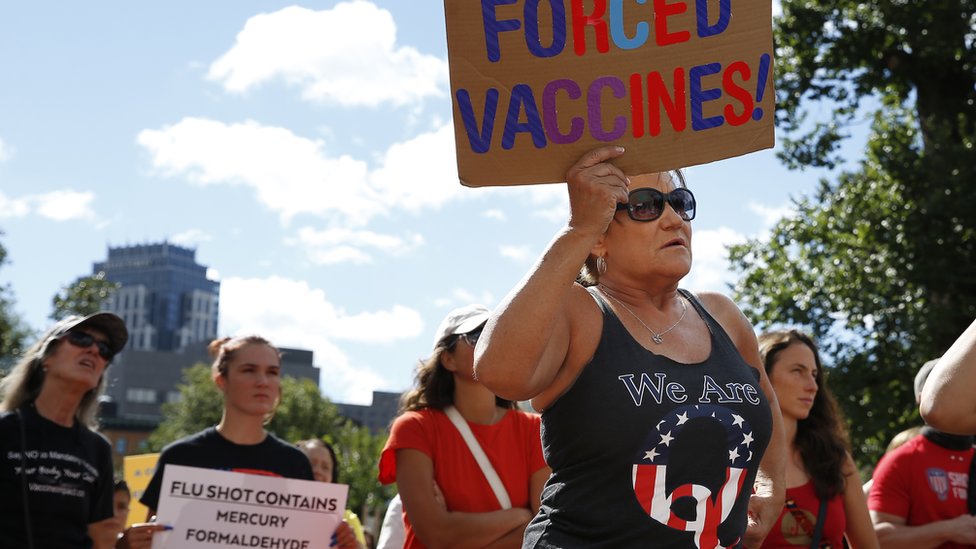 Протестующий против вакцинации в футболке QAnon в Бостоне в воскресенье