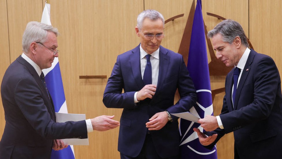 El candiller de Finlandia, Pekka Haavisto (izq) entrega los documentos de ingreso de su país a la OTAN al secretario de Estado de EE:UU., Antony Blinken, (der) y al secretario general de la organización, Jens Stoltenberg