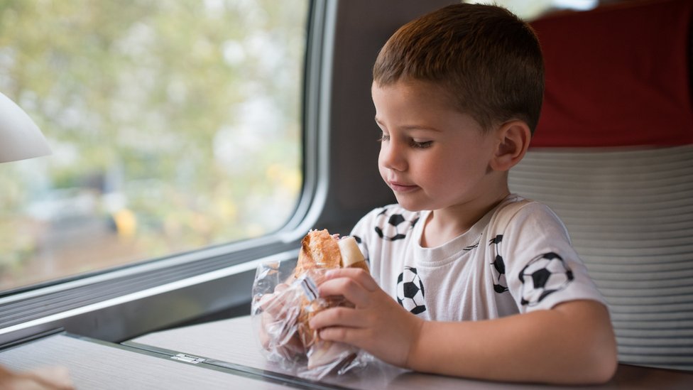 Мальчик ест бутерброд в поезде