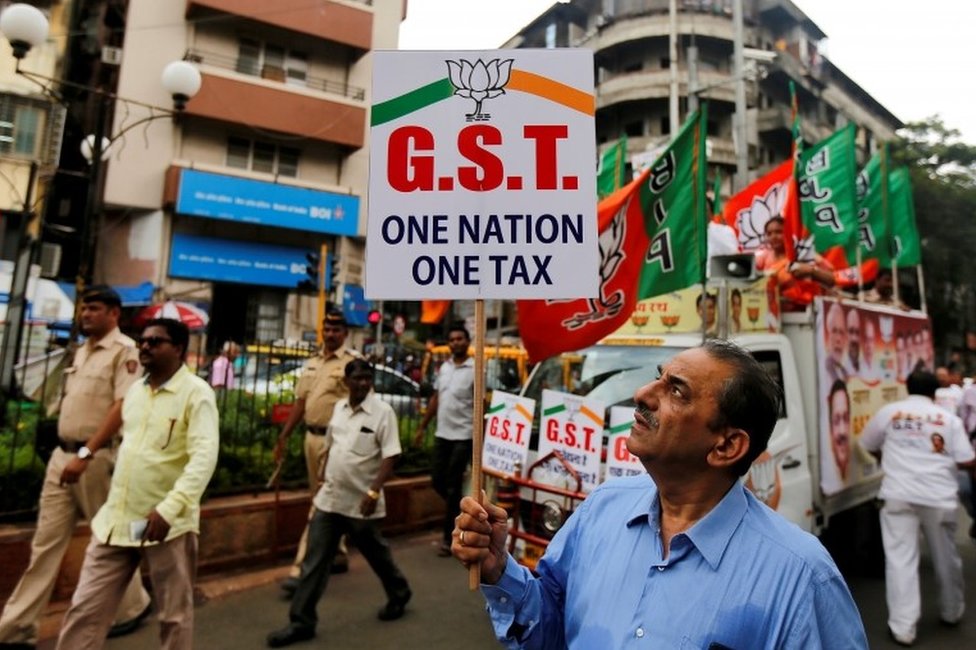 Сторонник правящей партии Индии Бхаратия Джаната (BJP) держит плакат во время митинга в поддержку введения налога на товары и услуги (GST) в Мумбаи, Индия, 30 июня 2017 г.